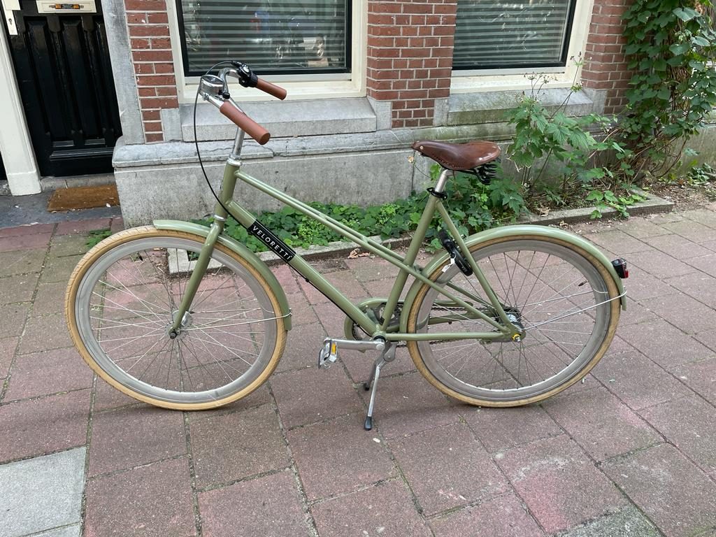 Olive-green Veloretti city bike parked on the street
